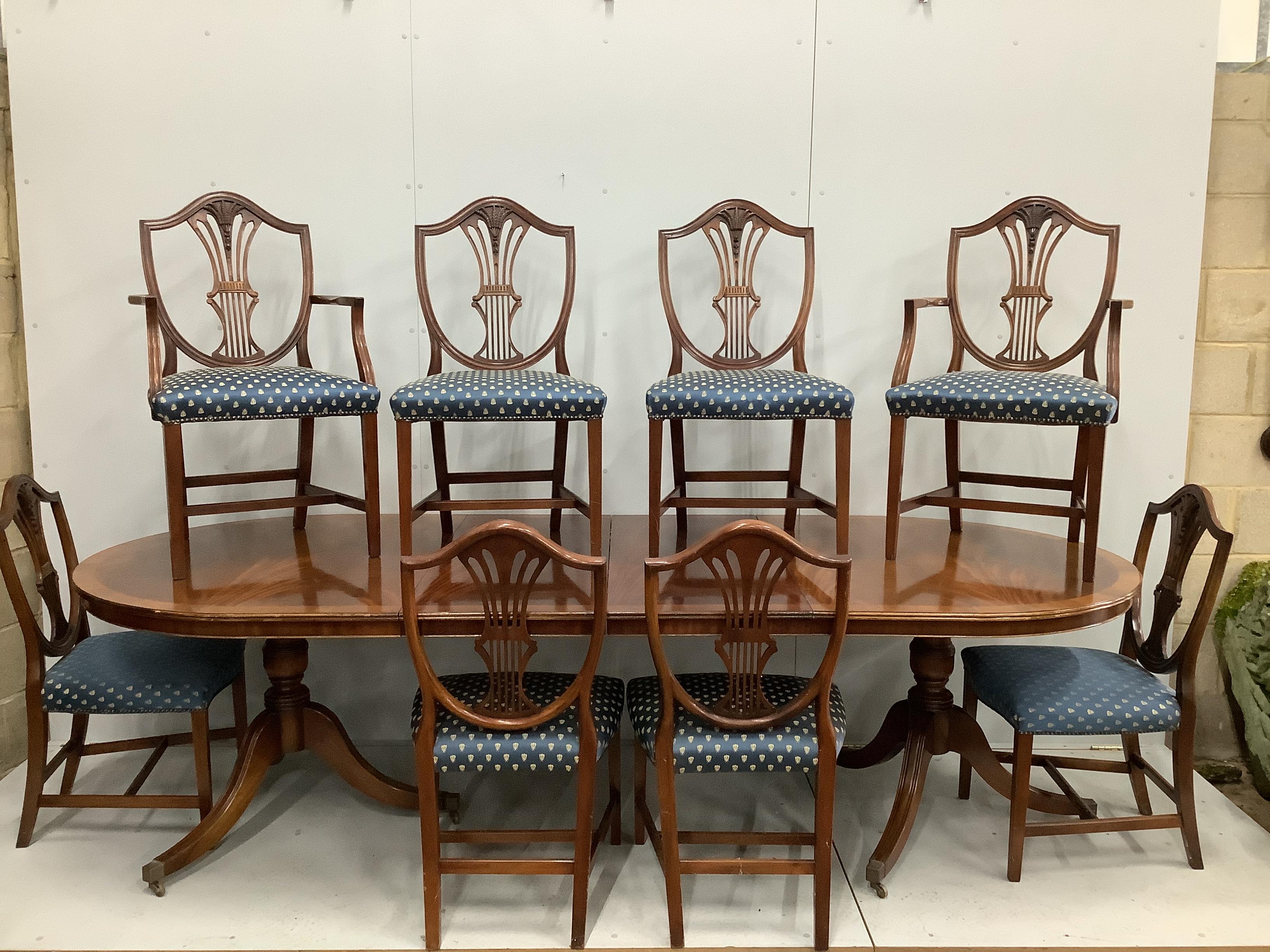 A reproduction mahogany twin pillar extending dining table, 276cm extended, two spare leaves, depth 115cm, height 75cm and eight Hepplewhite style shield back dining chairs, two with arms